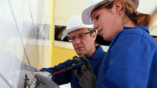 An electrician teaching an apprentice.